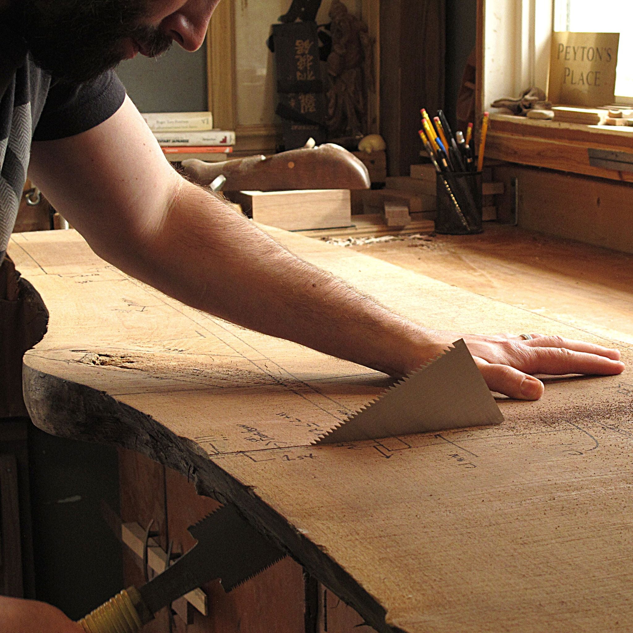 An expert furniture maker sawing a live edge wood slab for a custom modern console table at Mokuzai Furniture