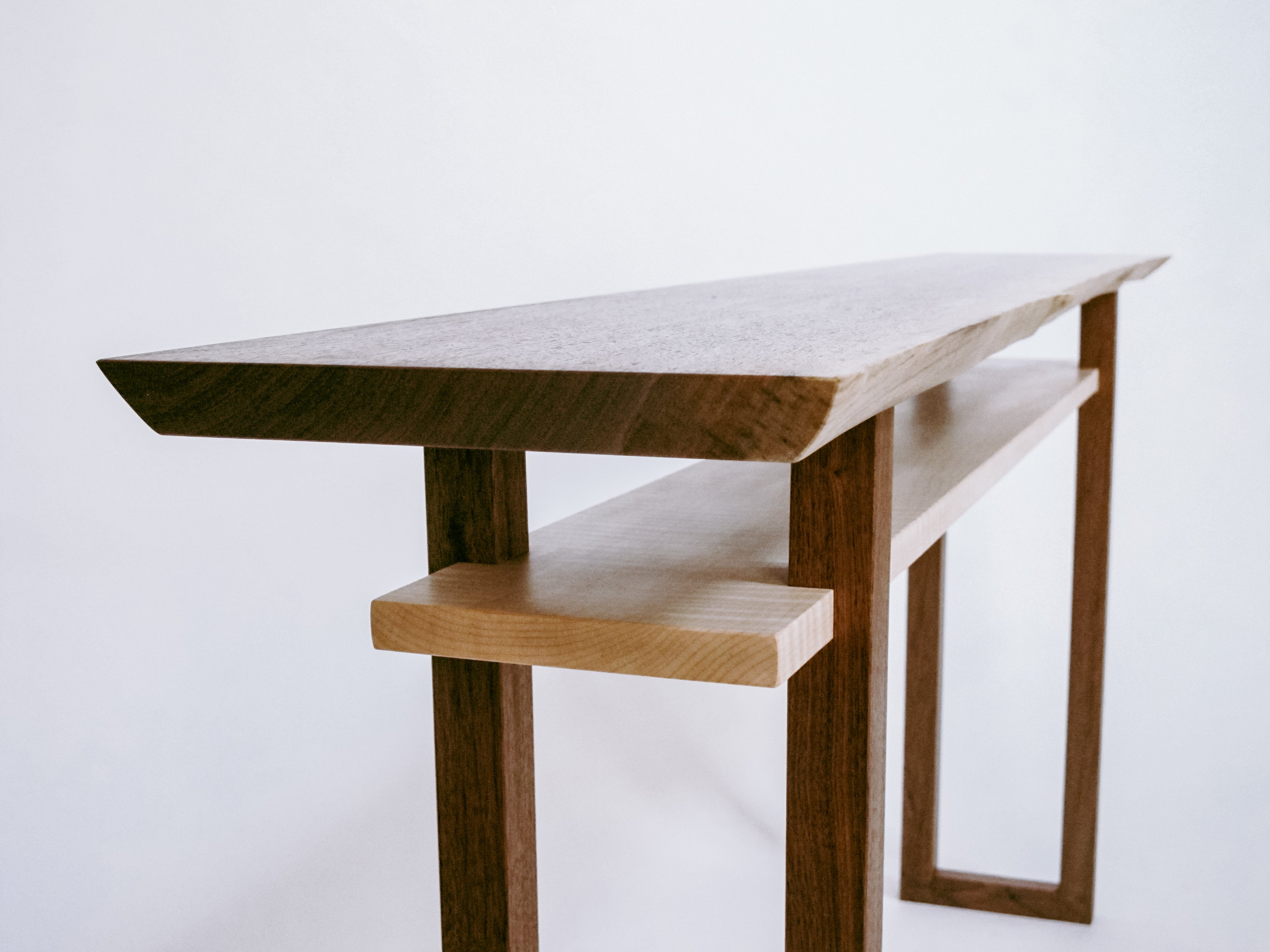 a live edge walnut console table with shelf in tiger maple. This modern wood furniture design is a unique console table option for hallways or entryways.