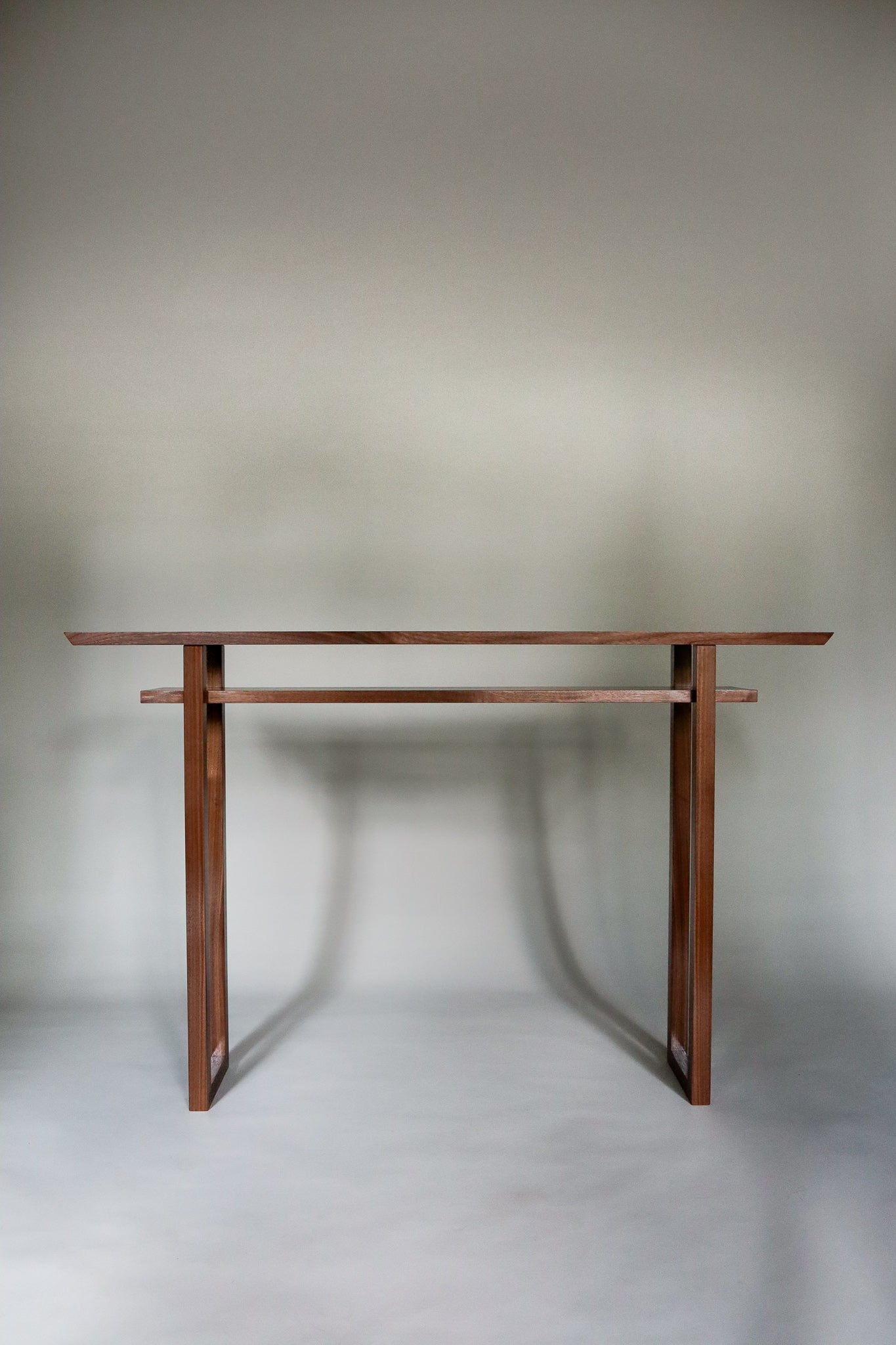 a modern console table for entryway decor or a narrow hall table. This narrow console table with shelf is handmade from solid walnut wood by Mokuzai Furniture.