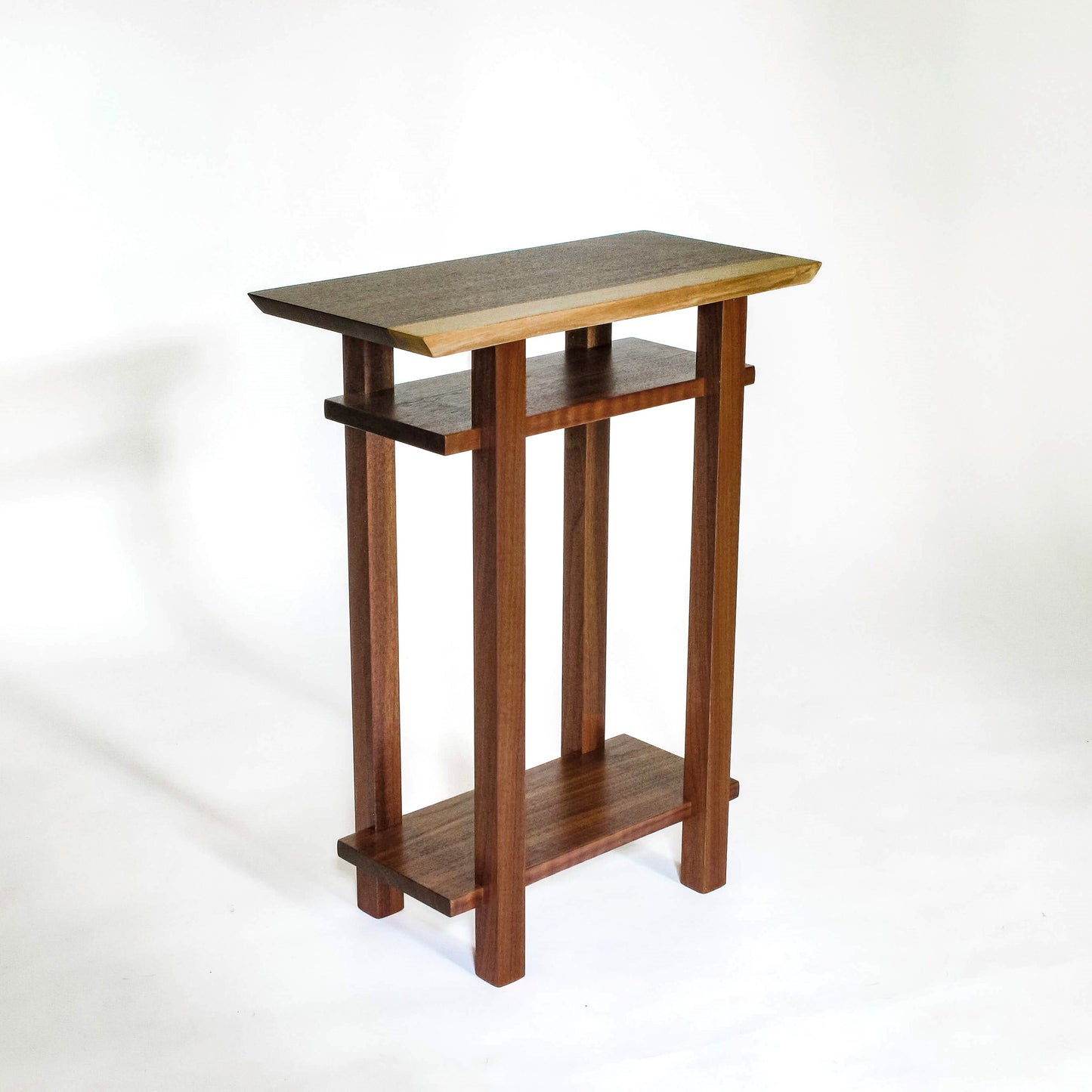 A small nightstand with shelves in solid walnut with a live edge walnut table top from Mokuzai Furniture.
