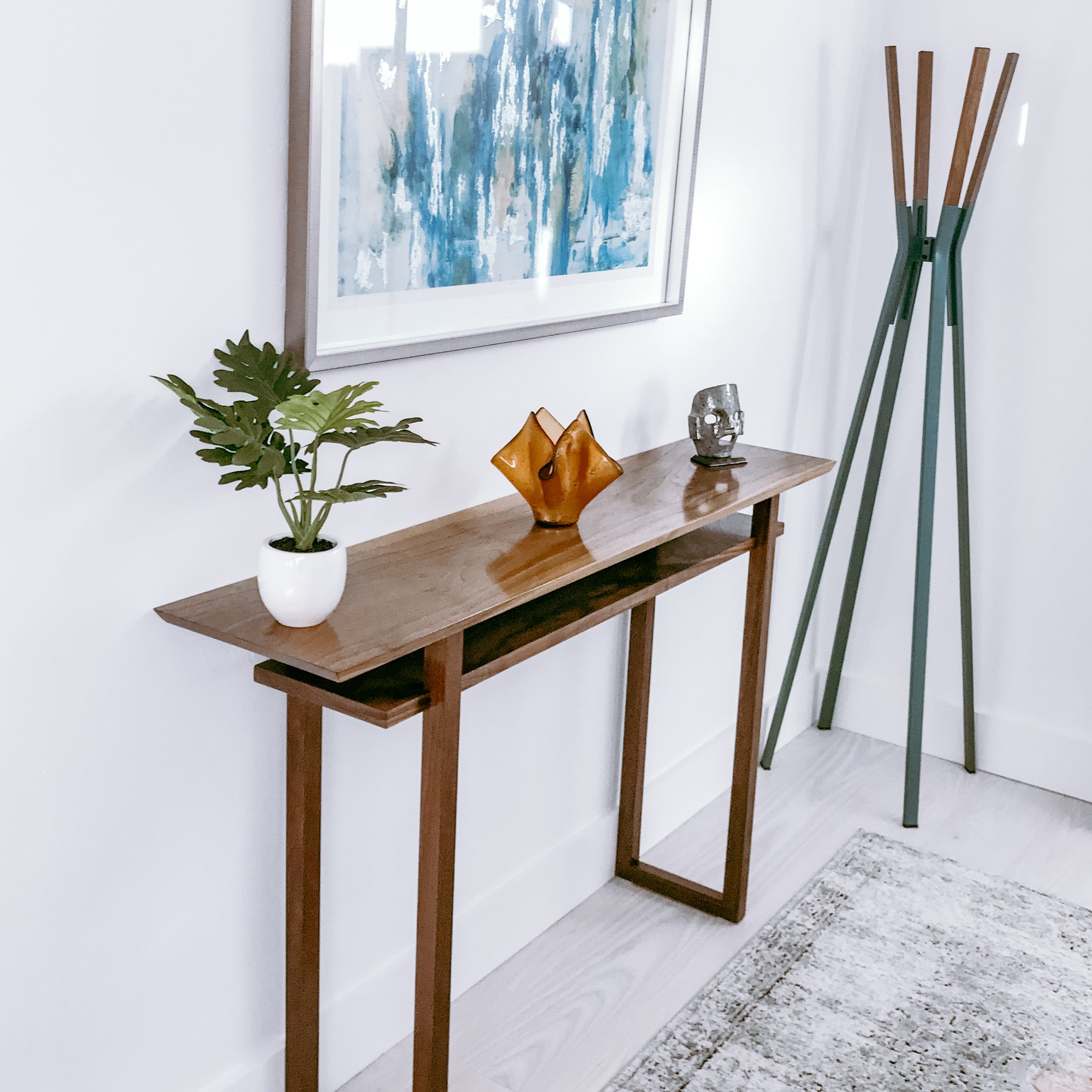 A narrow walnut console table with shelf in a modern entryway.  This modern console table is perfect for entryway decor or as a hallway table since it is a narrow console table and doesn't take up too much space