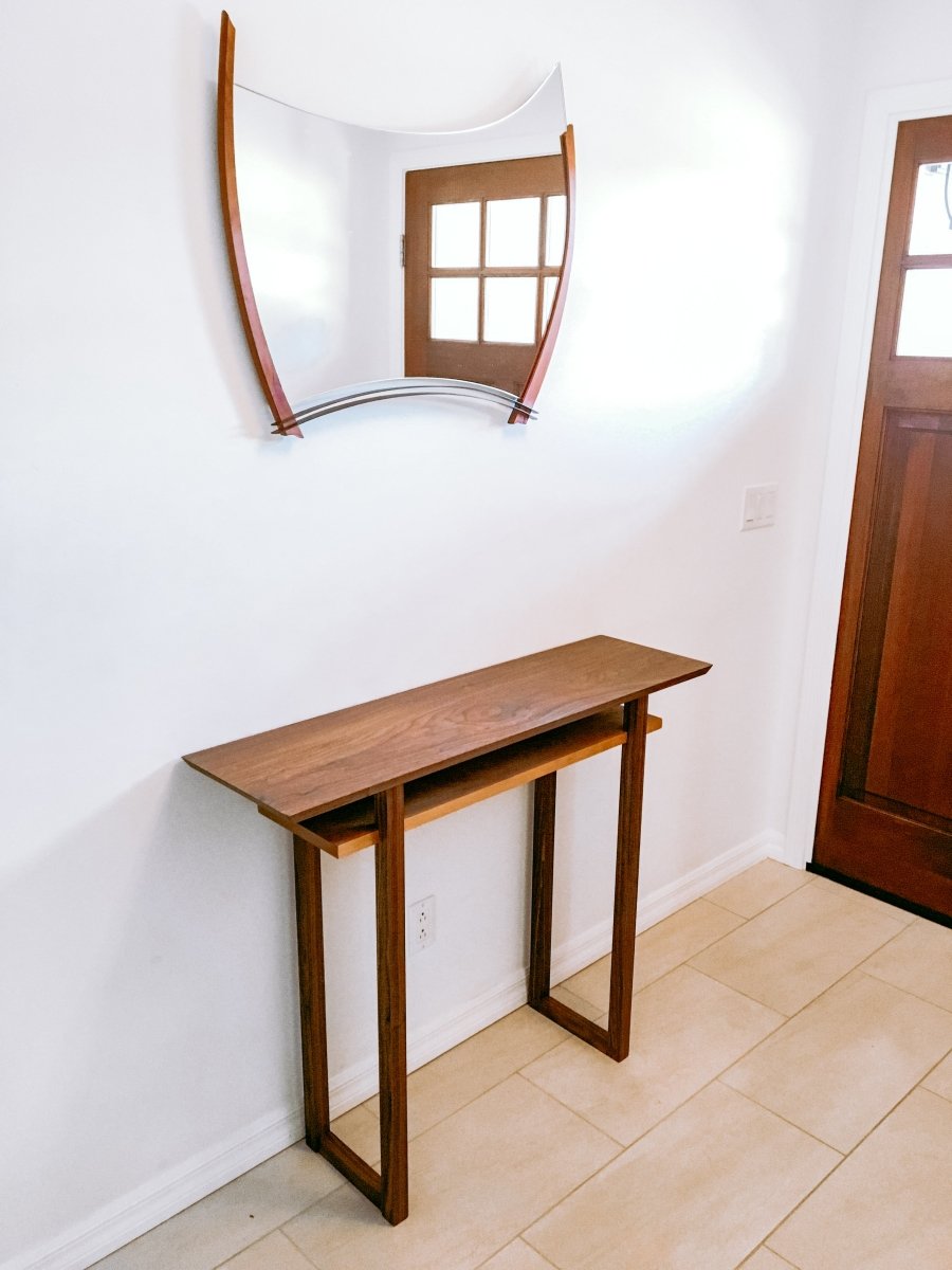 A modern entryway is decorated with a narrow console table from Mokuzai Furniture.