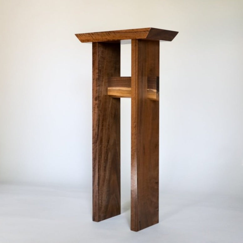 A small, tall entryway table handmade from solid walnut with a live edge table stretcher from Mokuzai Furniture.