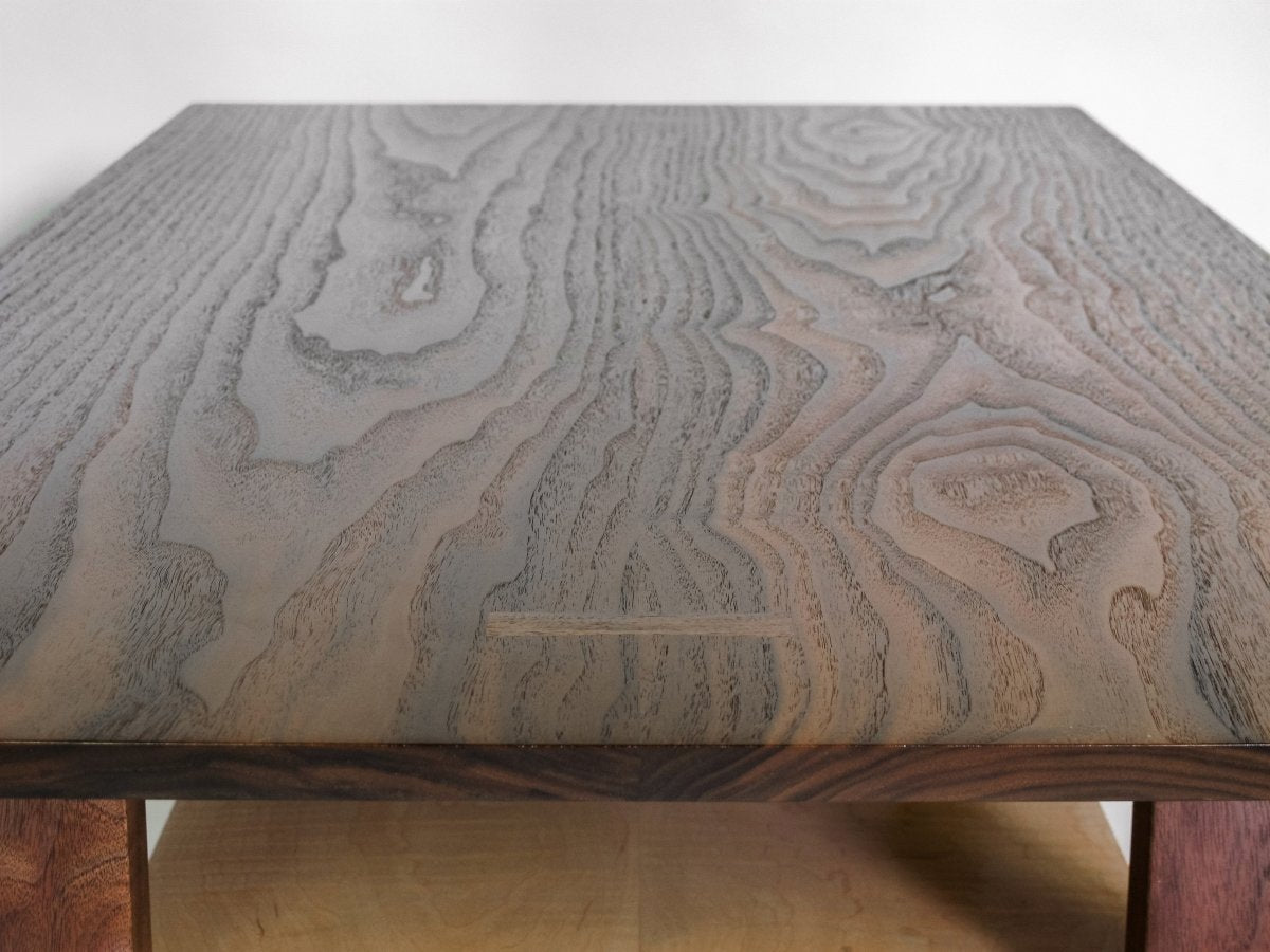 This modern coffee table has a walnut table top with beautiful butterfly key inlays at the ends. The shelf of this narrow coffee table offers storage for your living room decor. Modern wood furniture design by Mokuzai Furniture