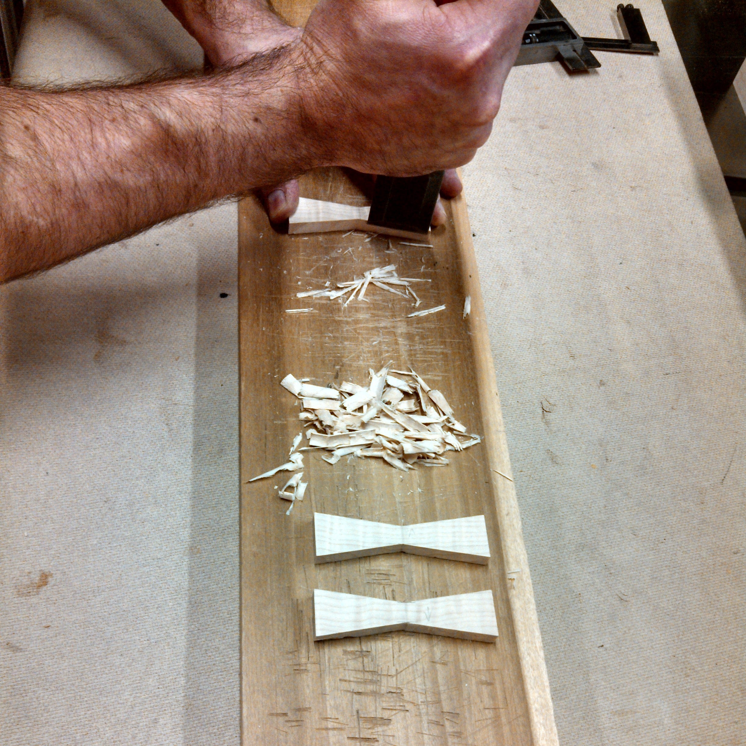 A furniture maker cuts butterfly key inlays with a chisel for a contemporary side table.