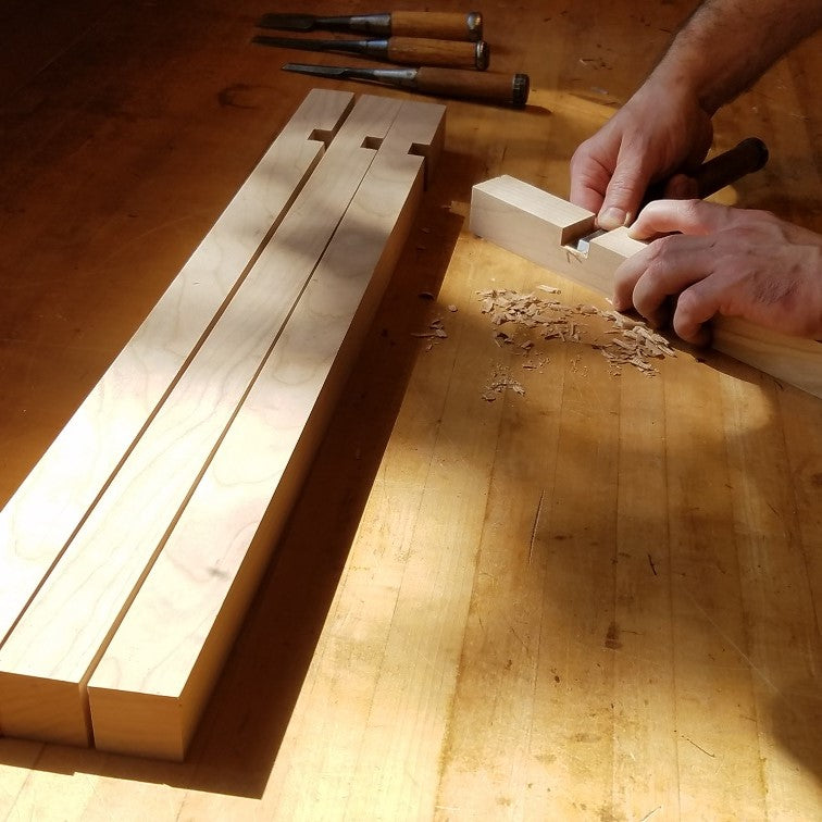 the joinery for the shelf of a custom end table is being cut with a chisel by the furniture artist at Mokuzai Furniture