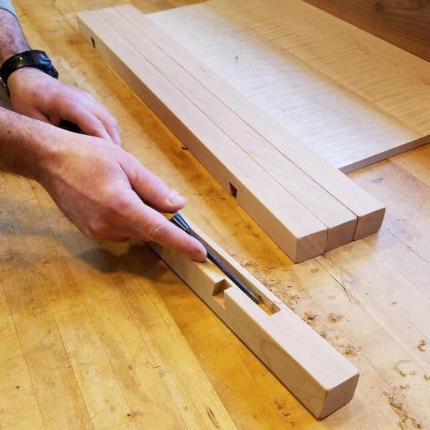 the furniture maker cleans the channel for panels on a side table at Mokuzai Furniture