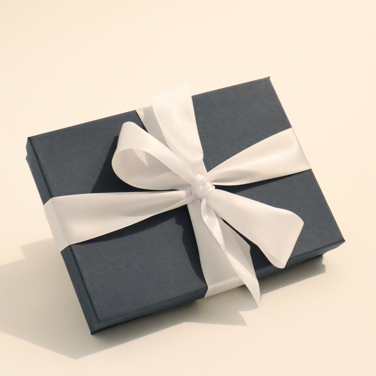 Blue gift box with a white ribbon holds a gift certificate for custom wood furniture from Mokuzai Furniture.