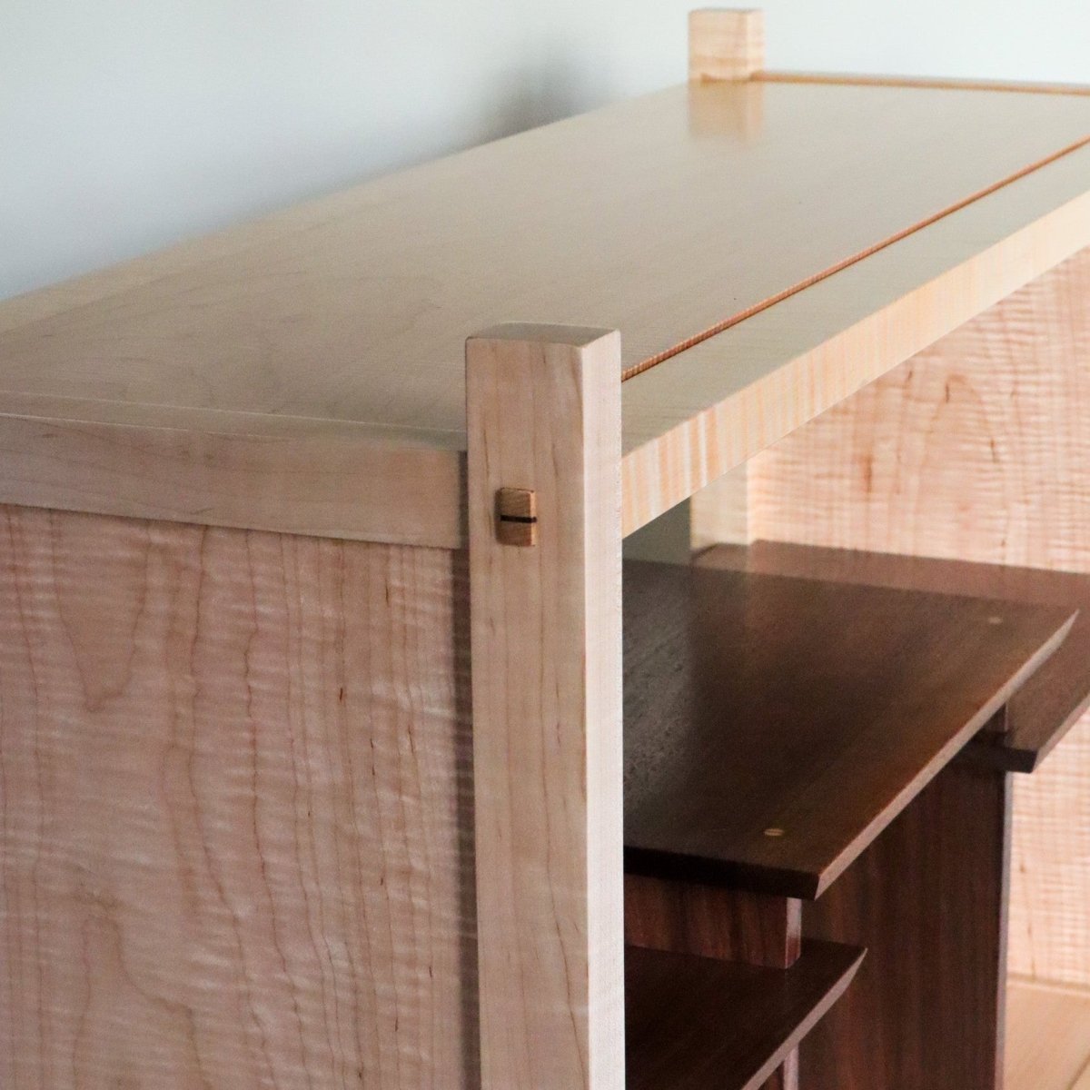 A modern media cabinet crafted from tiger maple with walnut display shelves from Mokuzai Furniture.