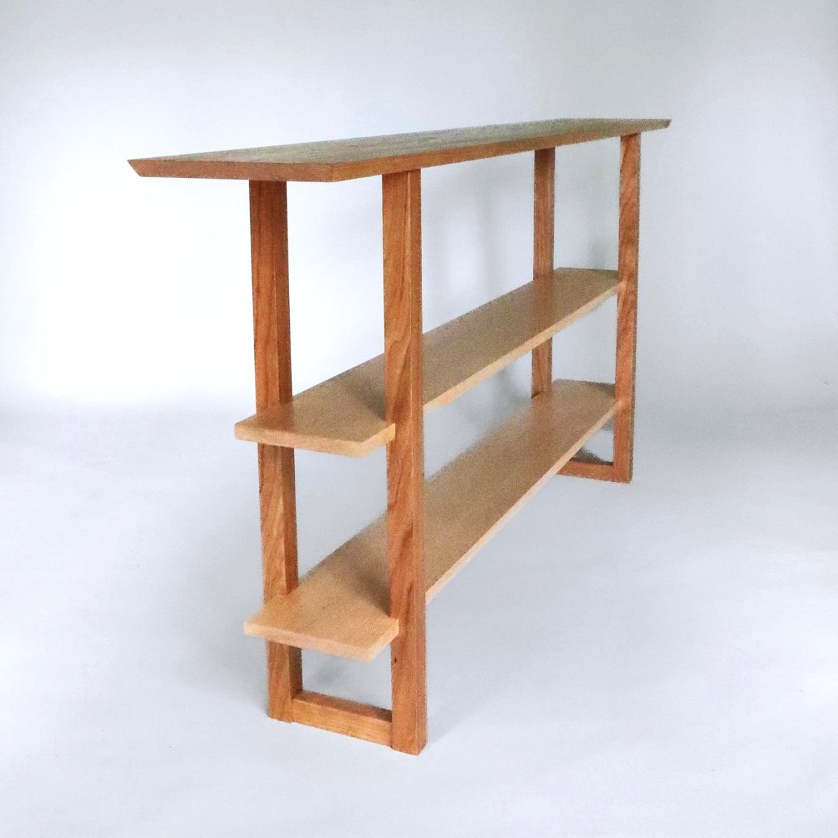 A modern narrow console table with two shelves for entryways and dining rooms from Mokuzai Furniture.