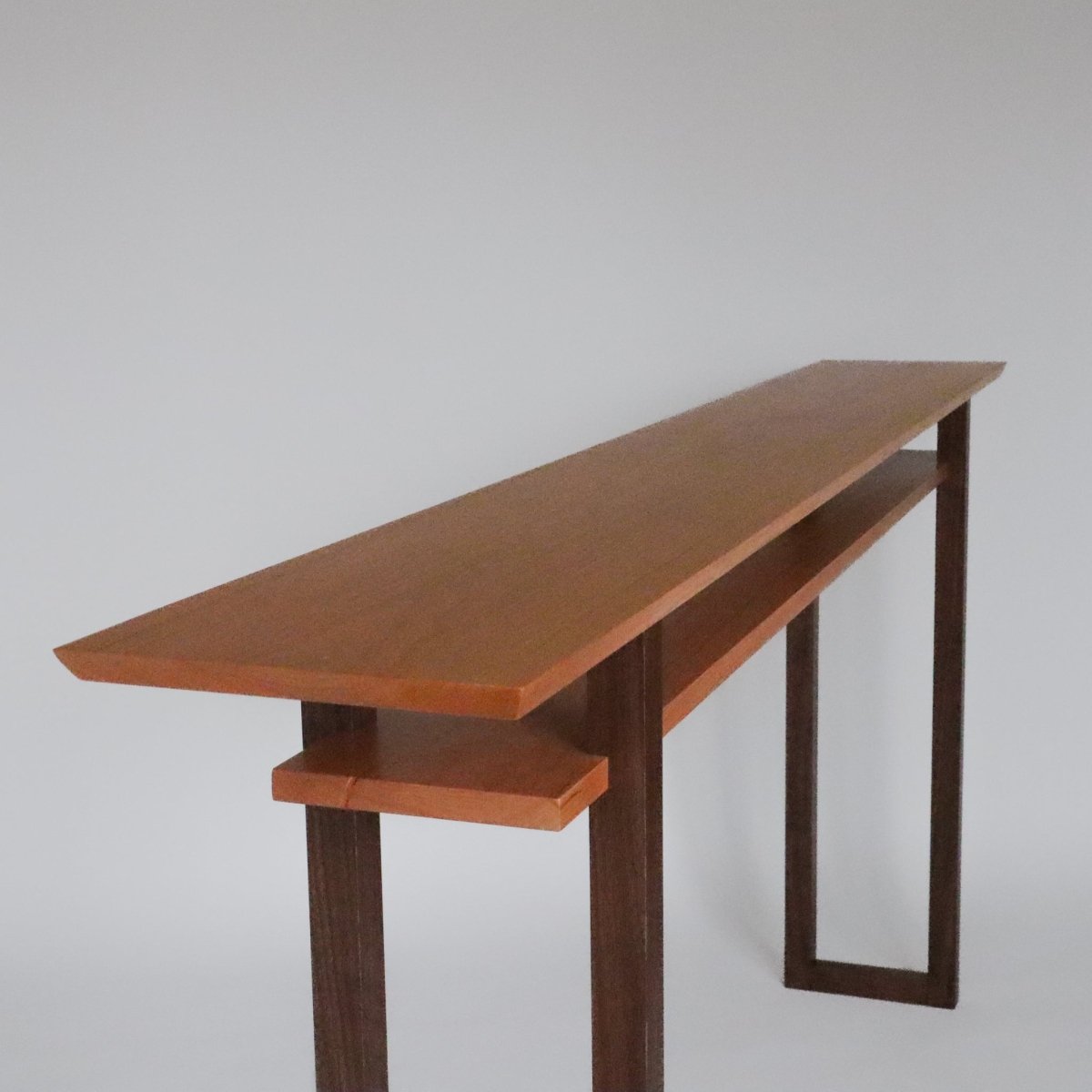 long narrow cherry console table with walnut legs by Mokuzai Furniture.