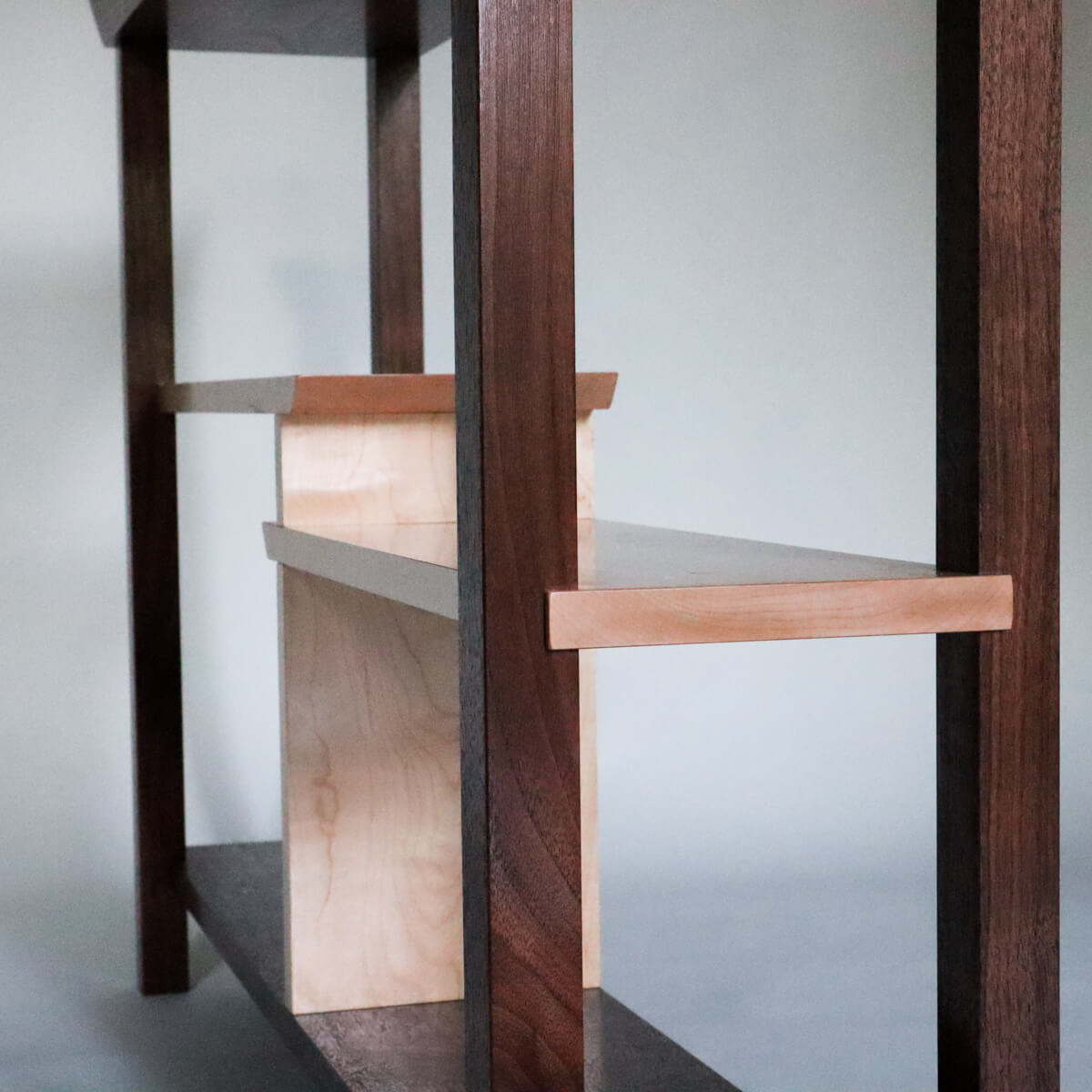 a narrow console table with staggered shelves by Mokuzai Furniture
