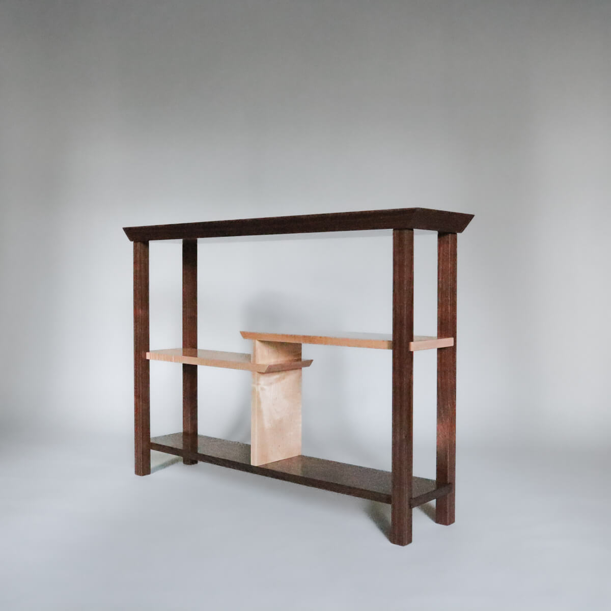 a narrow walnut console table with tiger maple shelves by Mokuzai Furniture
