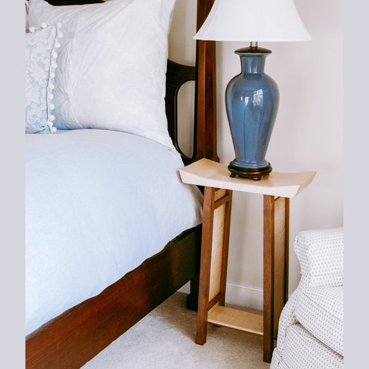 A unique bed side table with artistically shaped tabletop and low shelf for modern bedrooms by Mokuzai Furniture.