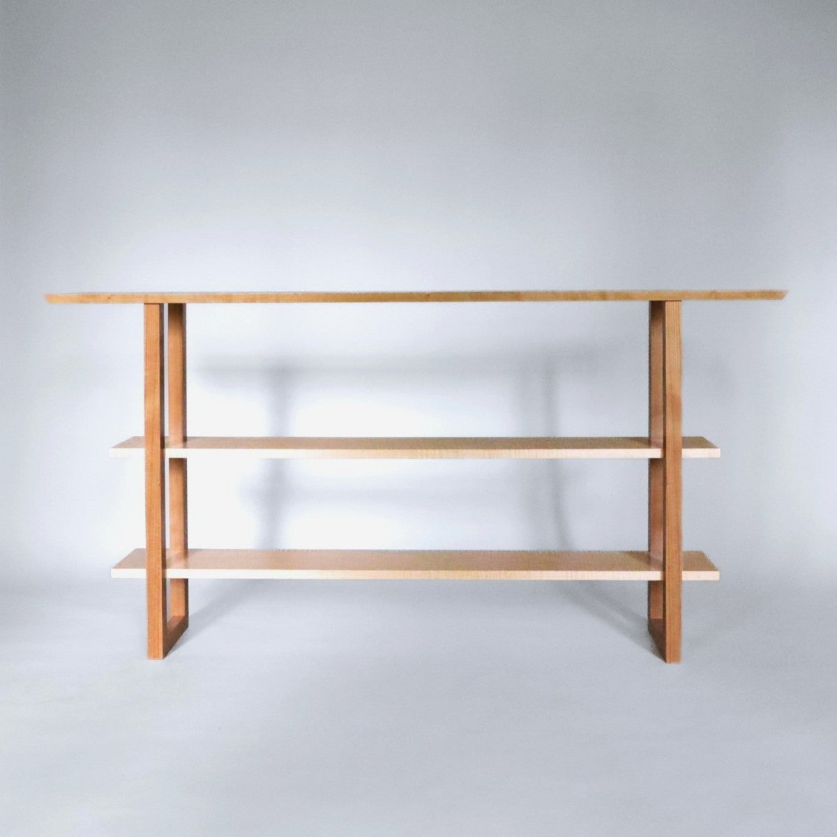 A tiered console table with shelves from cherry wood and tiger maple by Mokuzai Furniture.