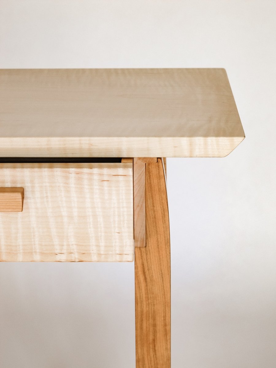 Unique joinery details on this luxury furniture design by Mokuzai Furniture.  A narrow end table with drawer in tiger maple and cherry.  Furniture thoughtfully sized for small space decorating.