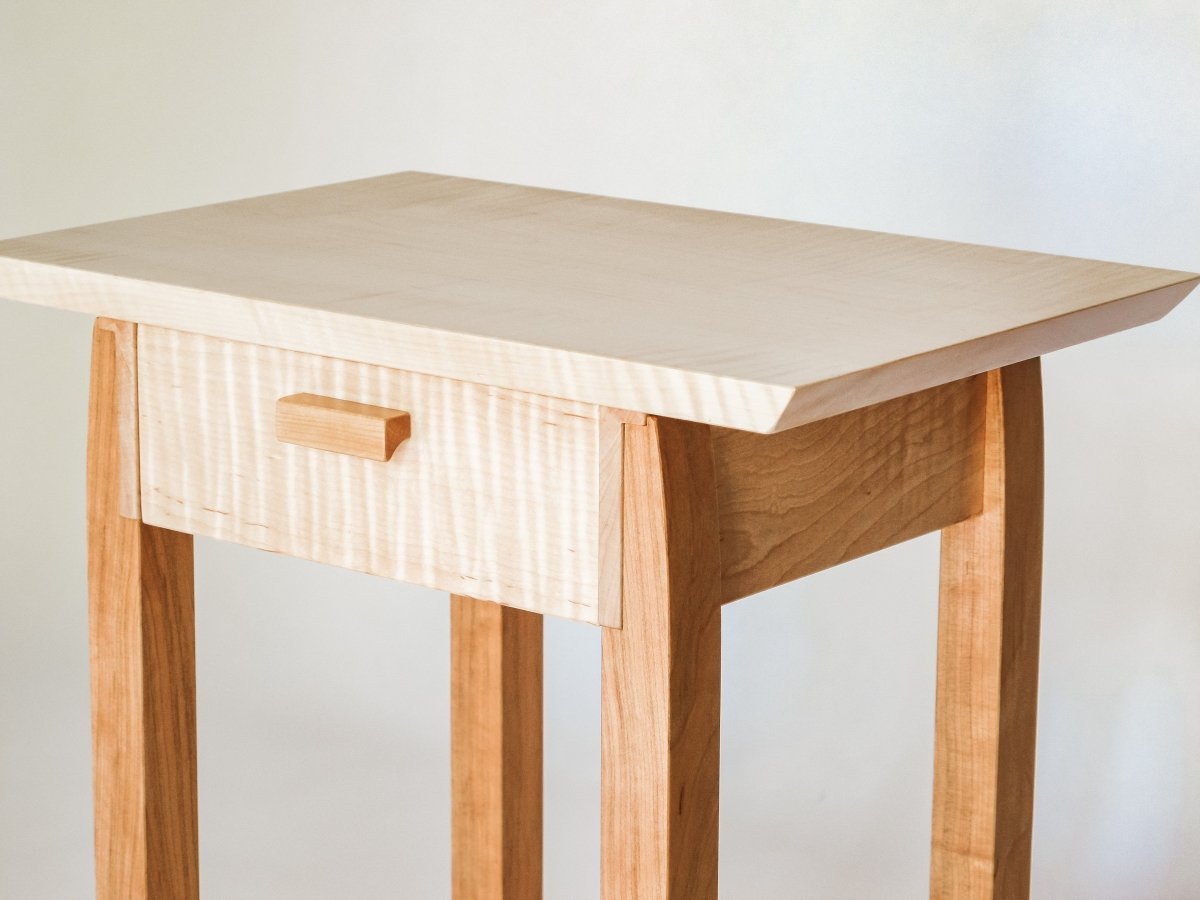 Contemporary wood furniture design by Mokuzai Furniture.  A narrow end table with drawer hand-crafted from solid wood in tiger maple and cherry.  Furniture designed for small spaces.  This modern end table with storage is a beautiful living room table or unique narrow nightstand.