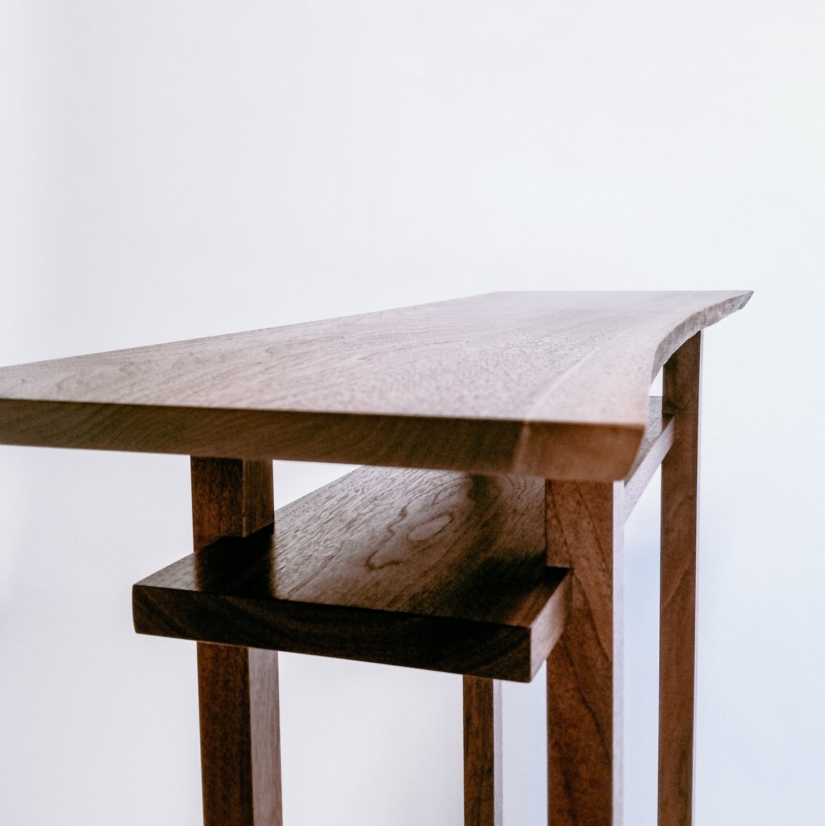 The natural shape of the growing tree is featured on the front edge of this artistic narrow console table