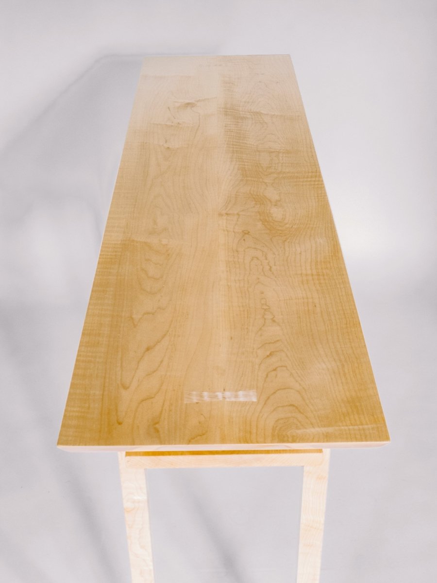 tiger maple table top with butterfly key inlays at the ends of this dining room console table with wine storage display shelf by Mokuzai Furniture