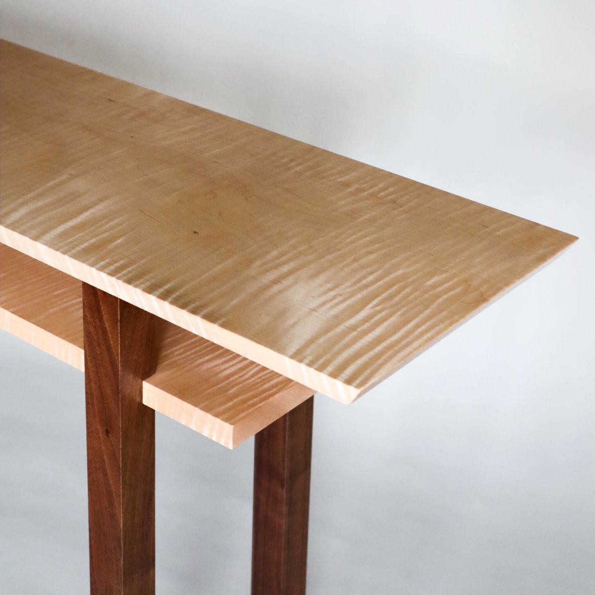 A unique console table hand-crafted from tiger maple wood with walnut table legs from Mokuzai Furniture