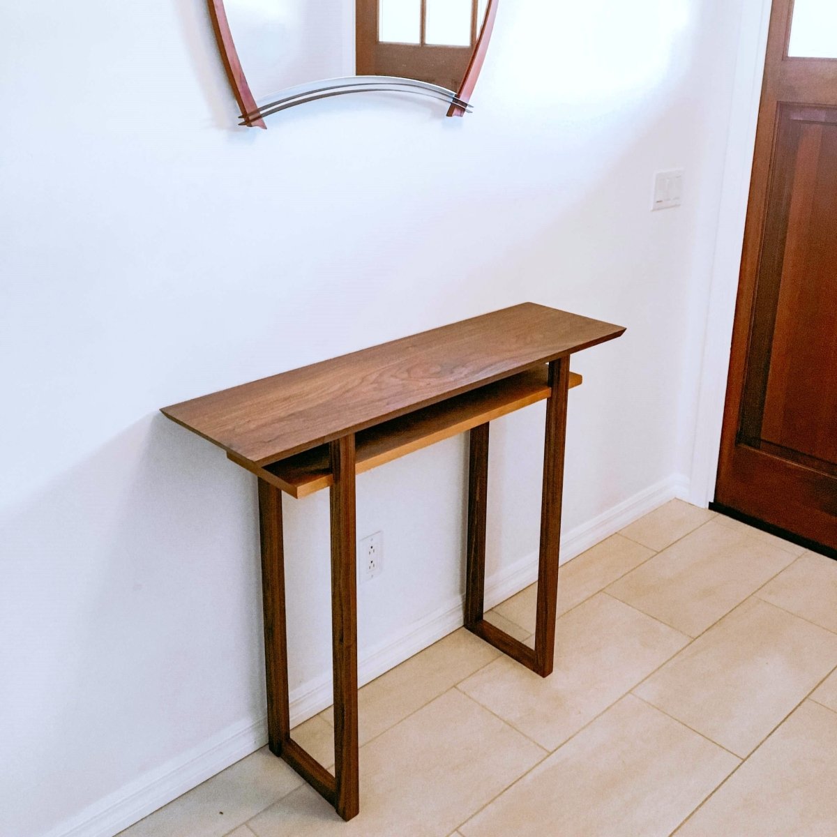 a bright entryway with a modern walnut and cherry hall table designed by Mokuzai Furniture